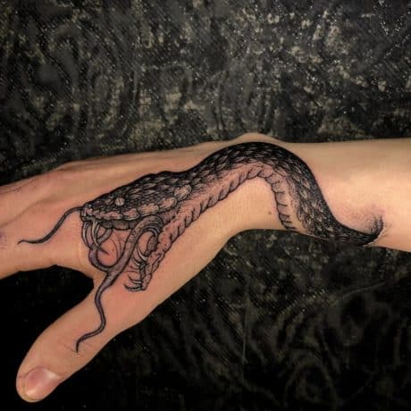 snake swallowing tattoo on hand 