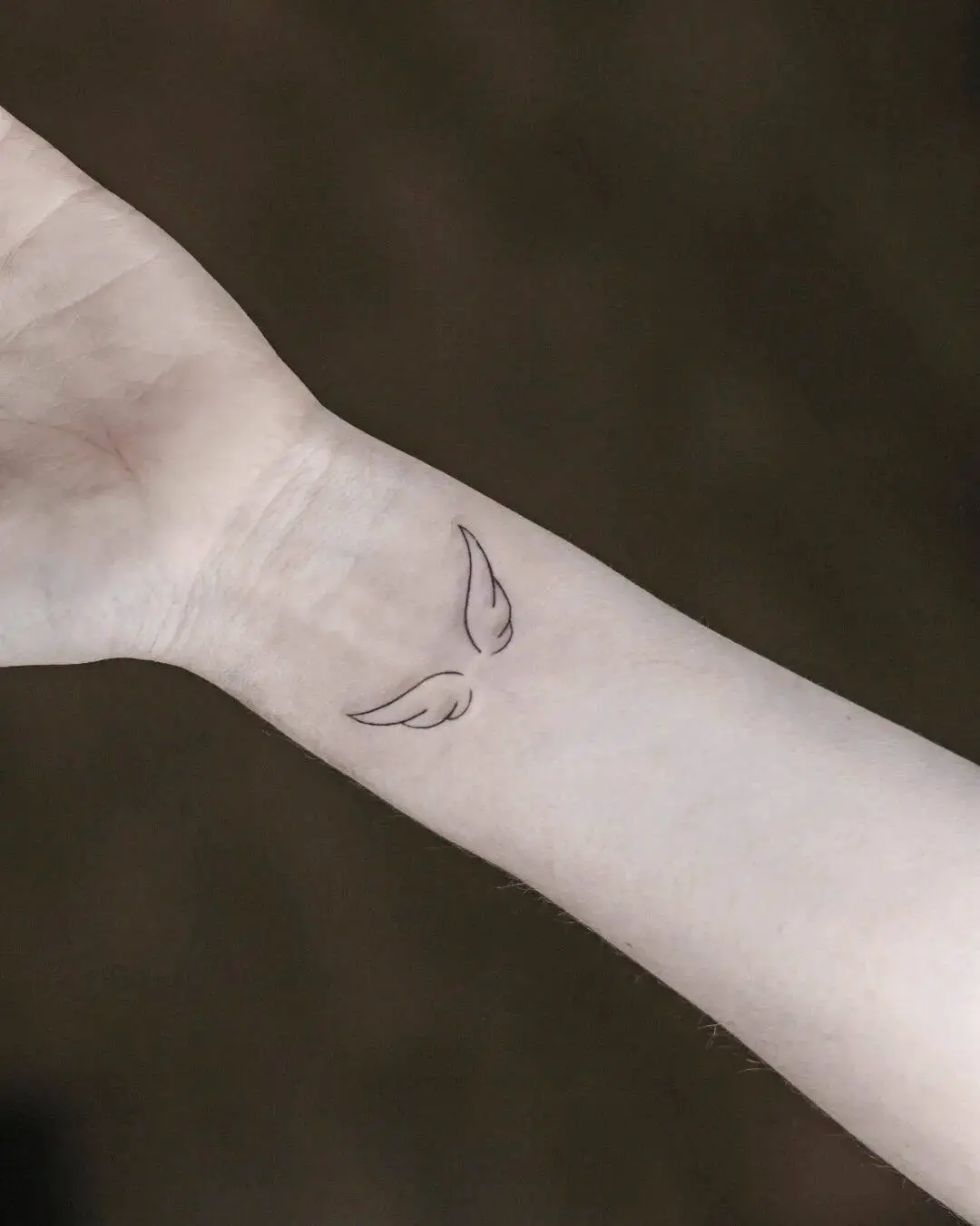 Minimalistic angel wing wrist tattoo