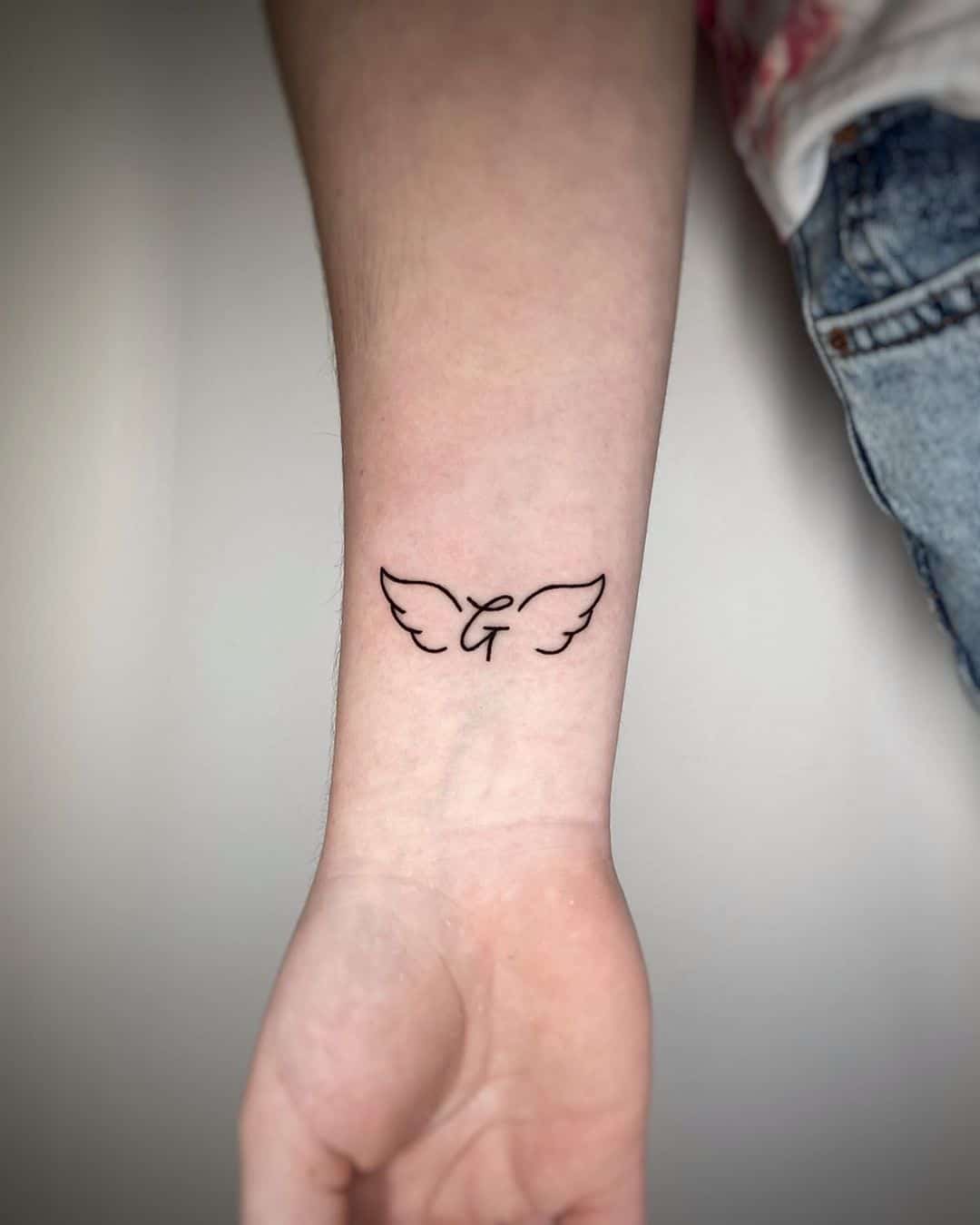Minimalistic angel wing wrist tattoo