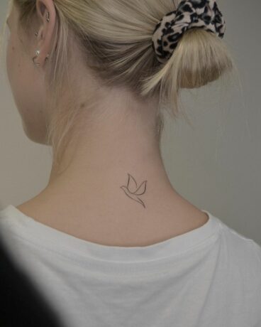 Small bird tattoo on neck by monochrom.ink