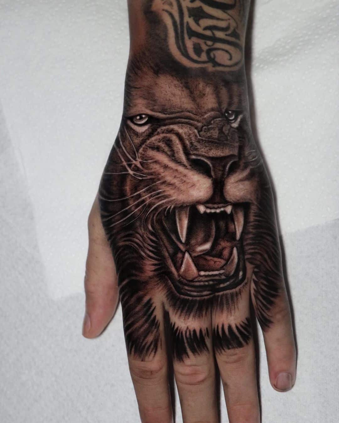 Black and gray lion tattoo on hand
