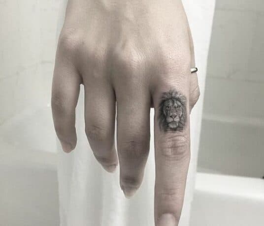 Mini lion on finger tattoo