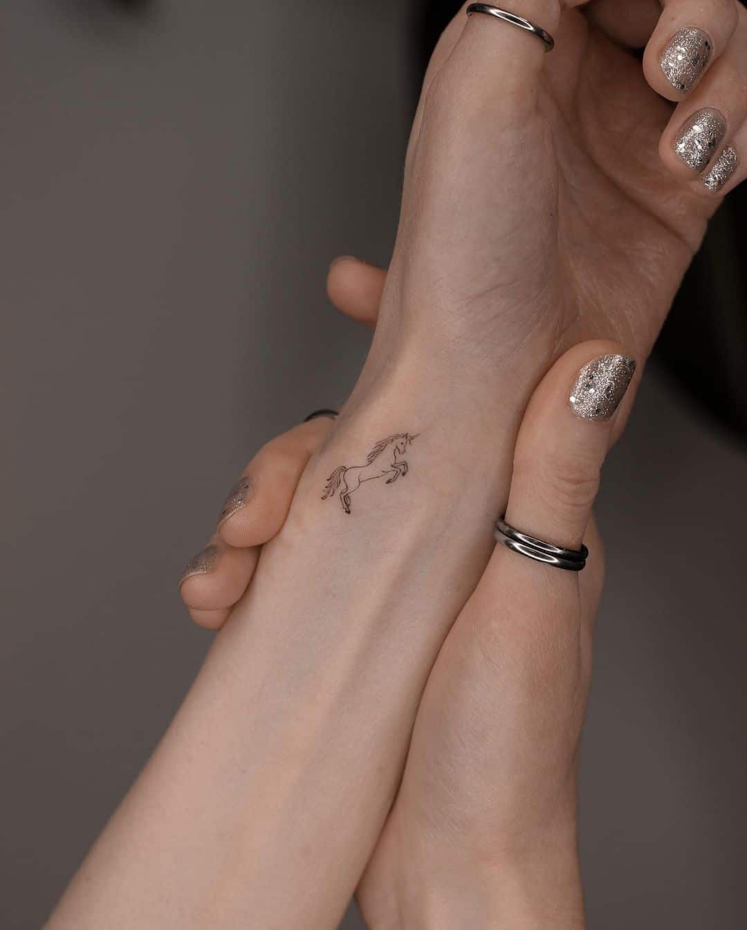 Minimalistic unicorn tattoo on rist by zd.tat