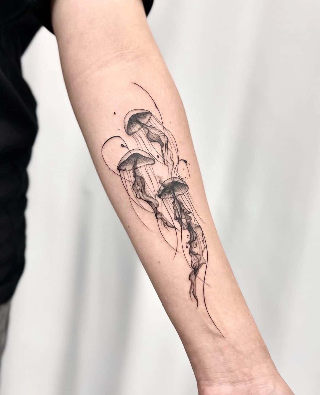 Fine line jellyfish tattoo located on the forearm.