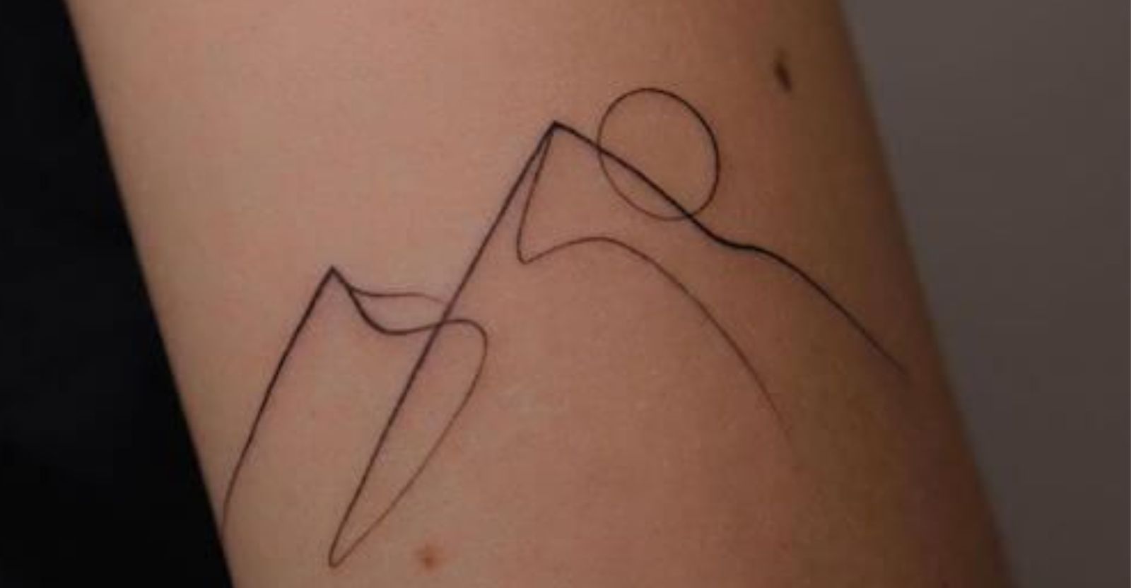 Minimalist mountain tattoo on lower back
