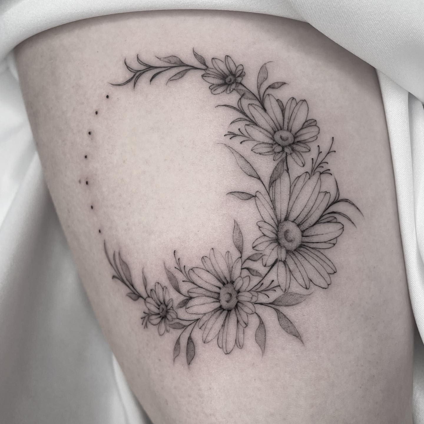 Micro-realistic daisy flowers tattooed on the upper