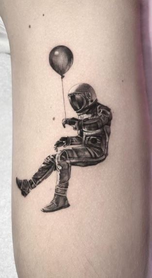 cute black and grey inked astronaut with balloon tattoo