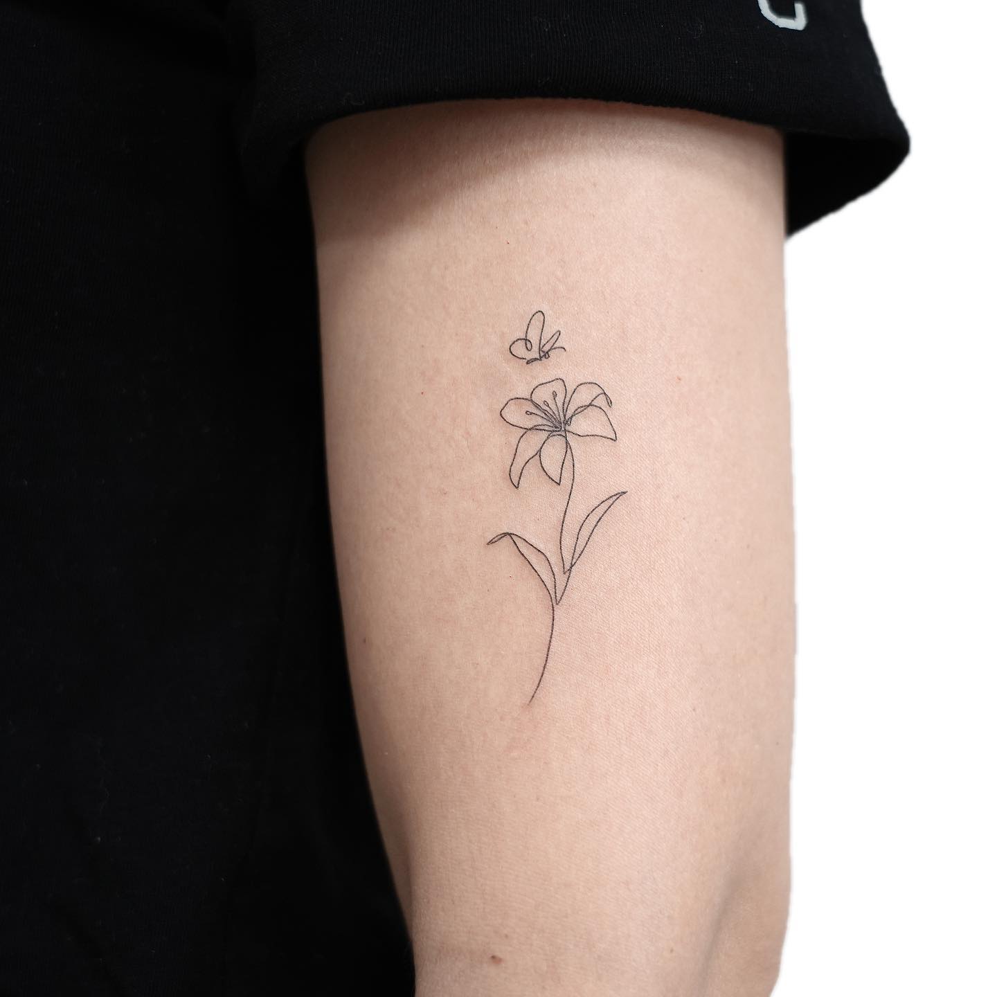 small lily flower tattoo by gigi tattooer