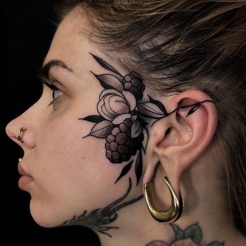 black inked flower tattoo on face