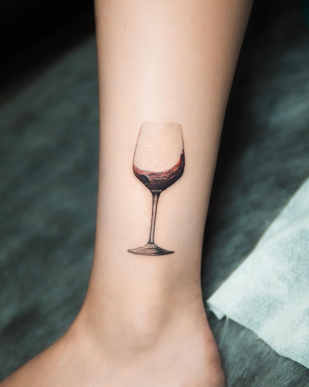 One line wine glass tattoo on the inner forearm.