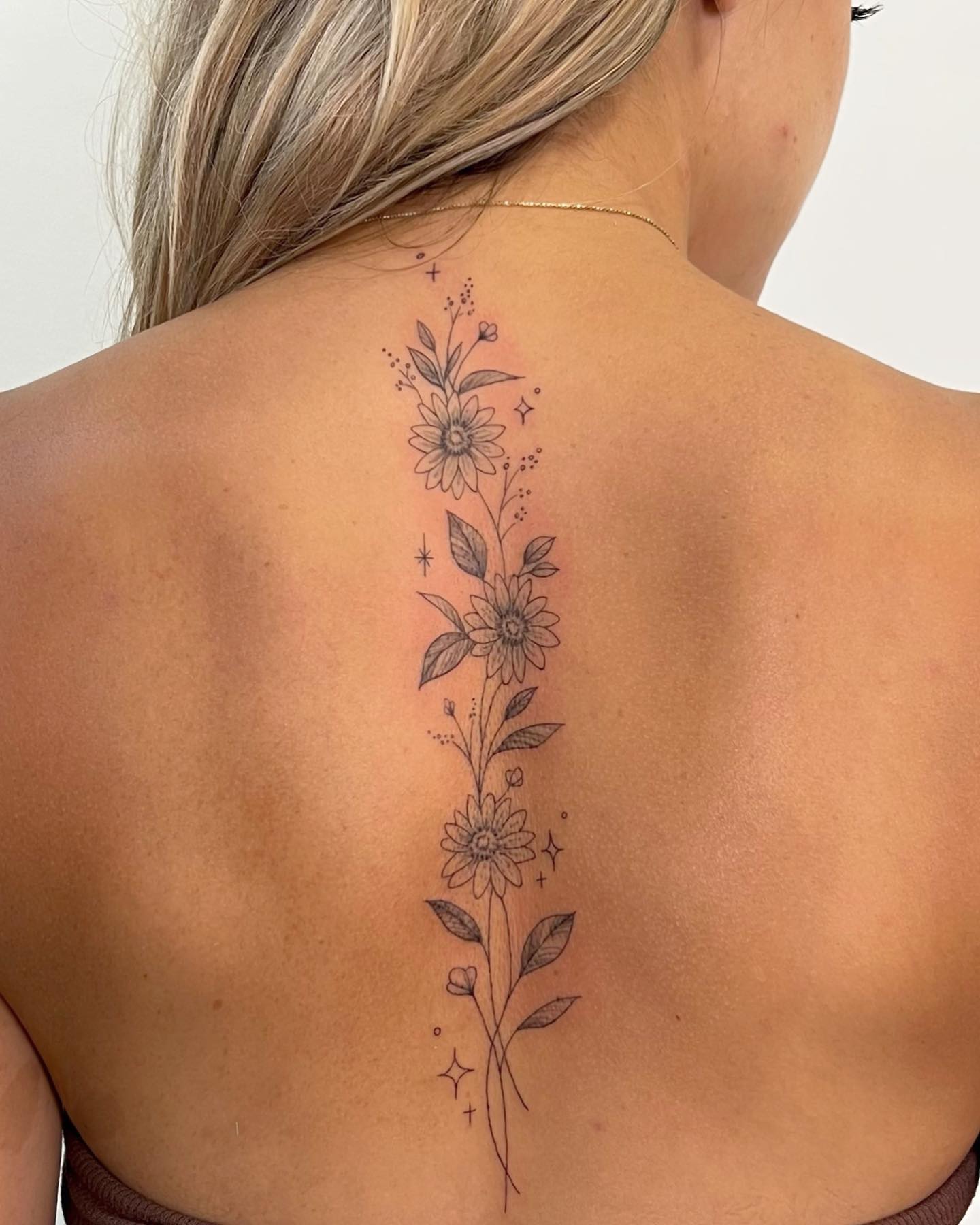 Floral spine design by wildflowers.tattoo